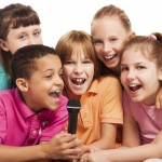 Close-up of a group of happy exited diversity looking kids, boys and girls, singing together sitting on the coach in living room